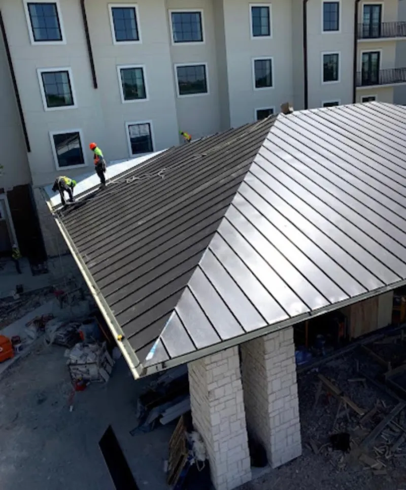 Crew installing standing seam metal roof panels on a commercial project in Yelm